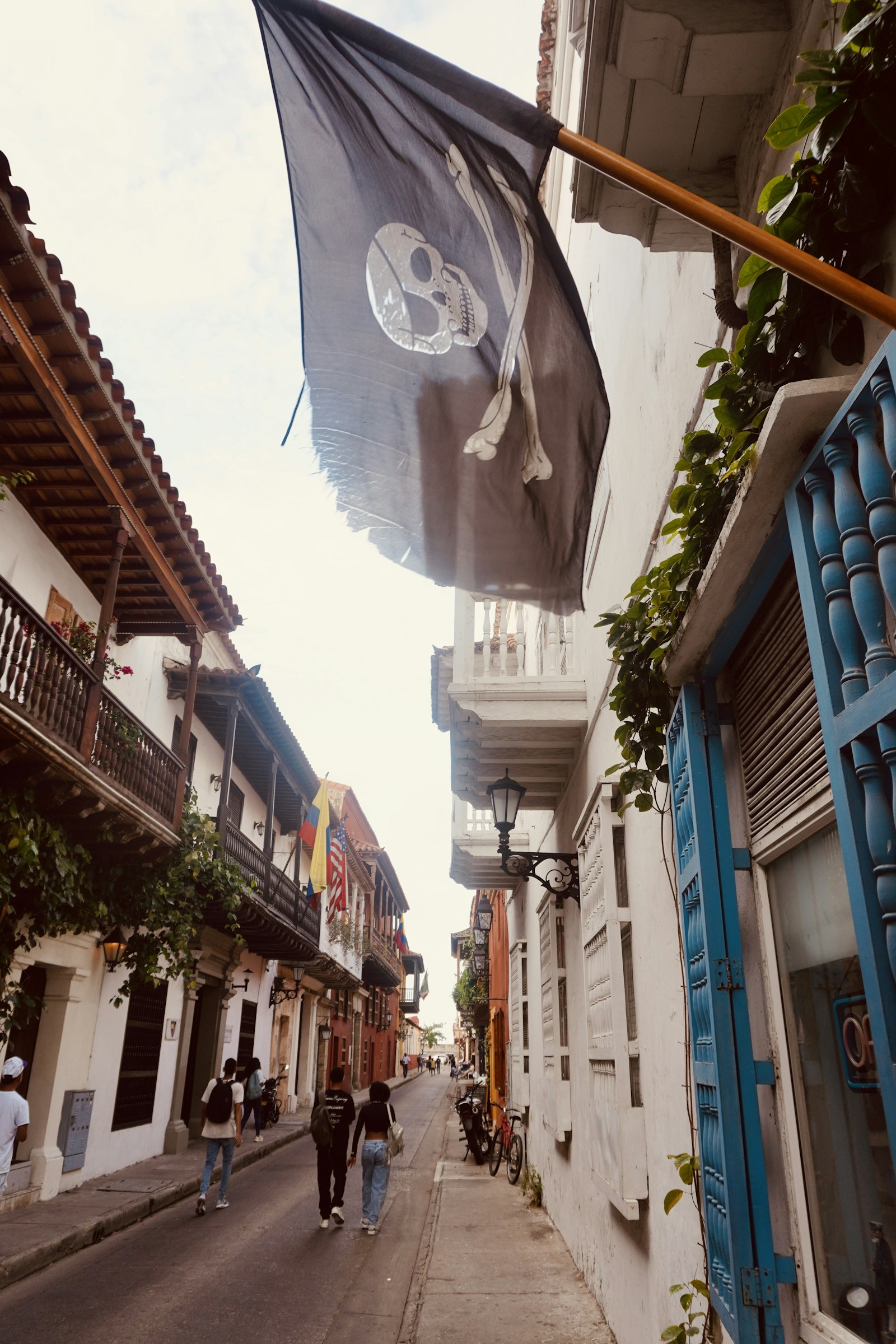A pirate flag waves over a narrow street.
