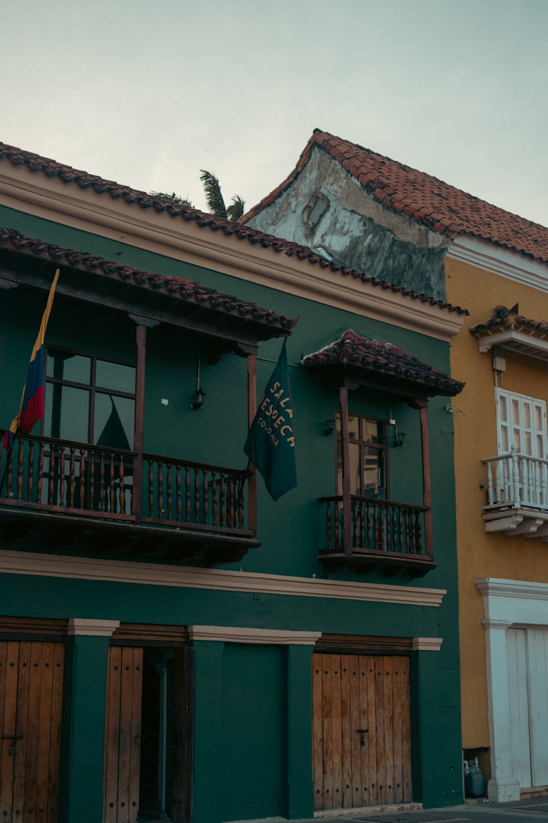 Green and yellow buildings with wooden balconies and flags.