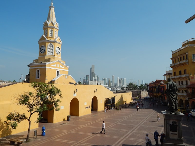 Yellow historic clock tower in a sunny plaza.