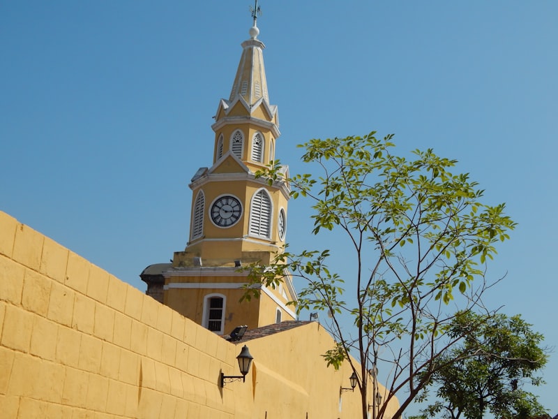 Yellow clock tower behind a textured wall